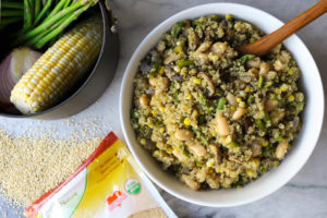 white bowl filled with asparagus mushroom quinoa and wooden serving spoon