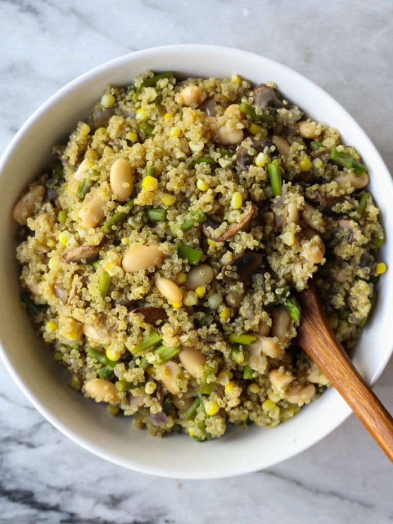 white bowl filled with asparagus mushroom quinoa and wooden spoon
