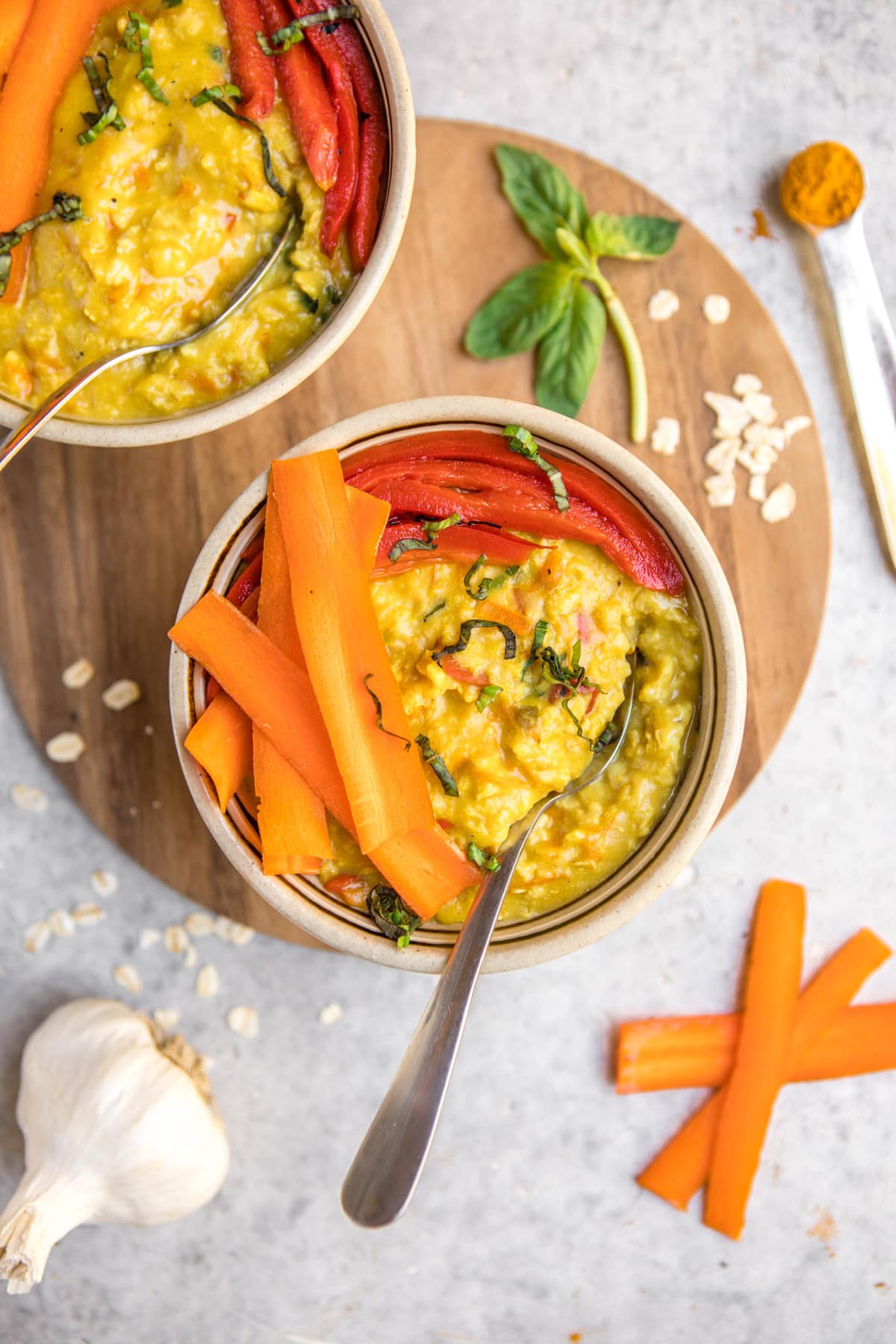 bowl of golden savory oatmeal topped with carrots and roasted red peppers