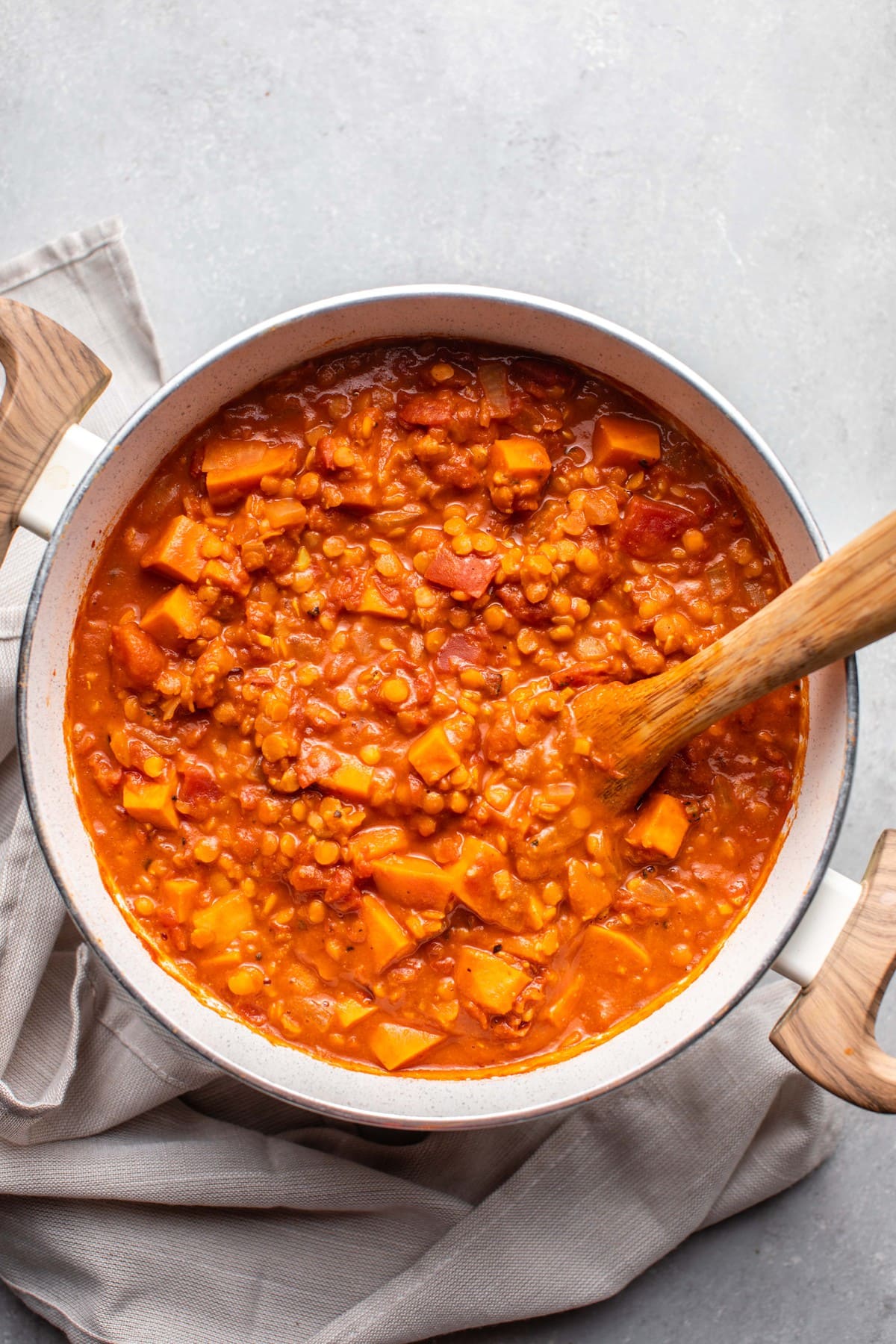 pot of sweet potato red lentil and peanut stew with wooden spoon