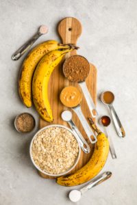 ingredients for banana bread in measuring cups on long wooden serving board