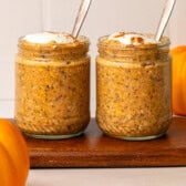 two glass jars of pumpkin spice latte overnight oats topped with cashew cream and cinnamon