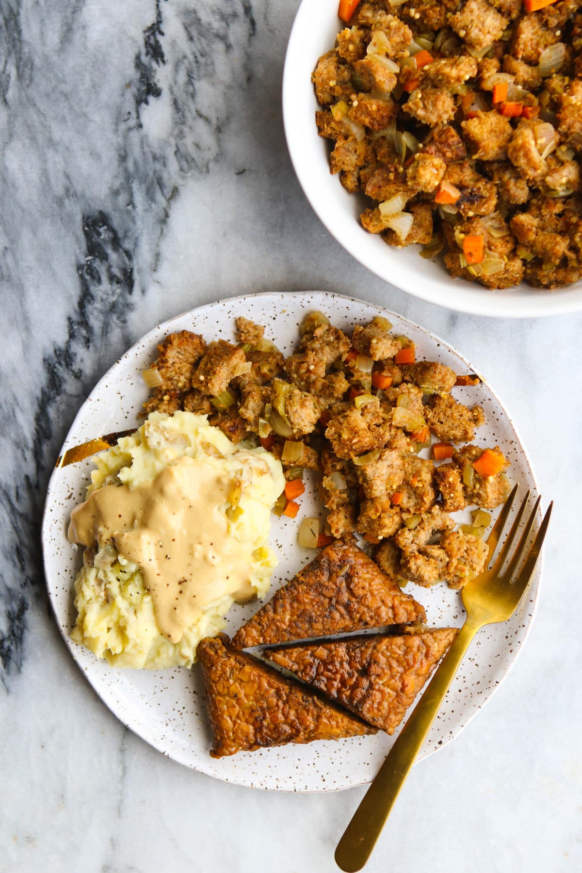 white plate filled with mashed potatoes, gravy, tempeh, and stovetop stuffing 