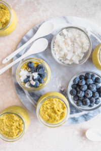top view of golden milk chia pudding jars with blueberries and coconut