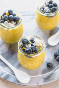 assembled golden milk chia pudding jars with blueberries and coconut