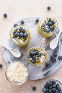 top view of golden milk chia pudding jars with blueberries and coconut