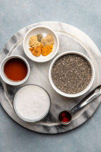 ingredients for golden milk chia seed pudding in small dishes on marble serving board