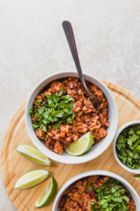 bowl of rice and beans on wood cutting board with lime