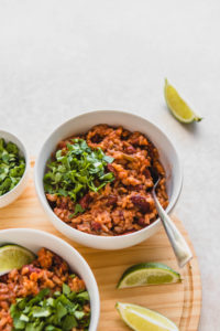 bowl of rice and beans on wood cutting board with lime
