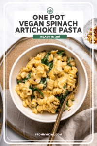 bowl of spinach artichoke pasta with gold fork