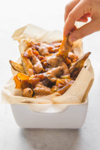 Vegan Animal Style Fries with Special Sauce in white container and hand
