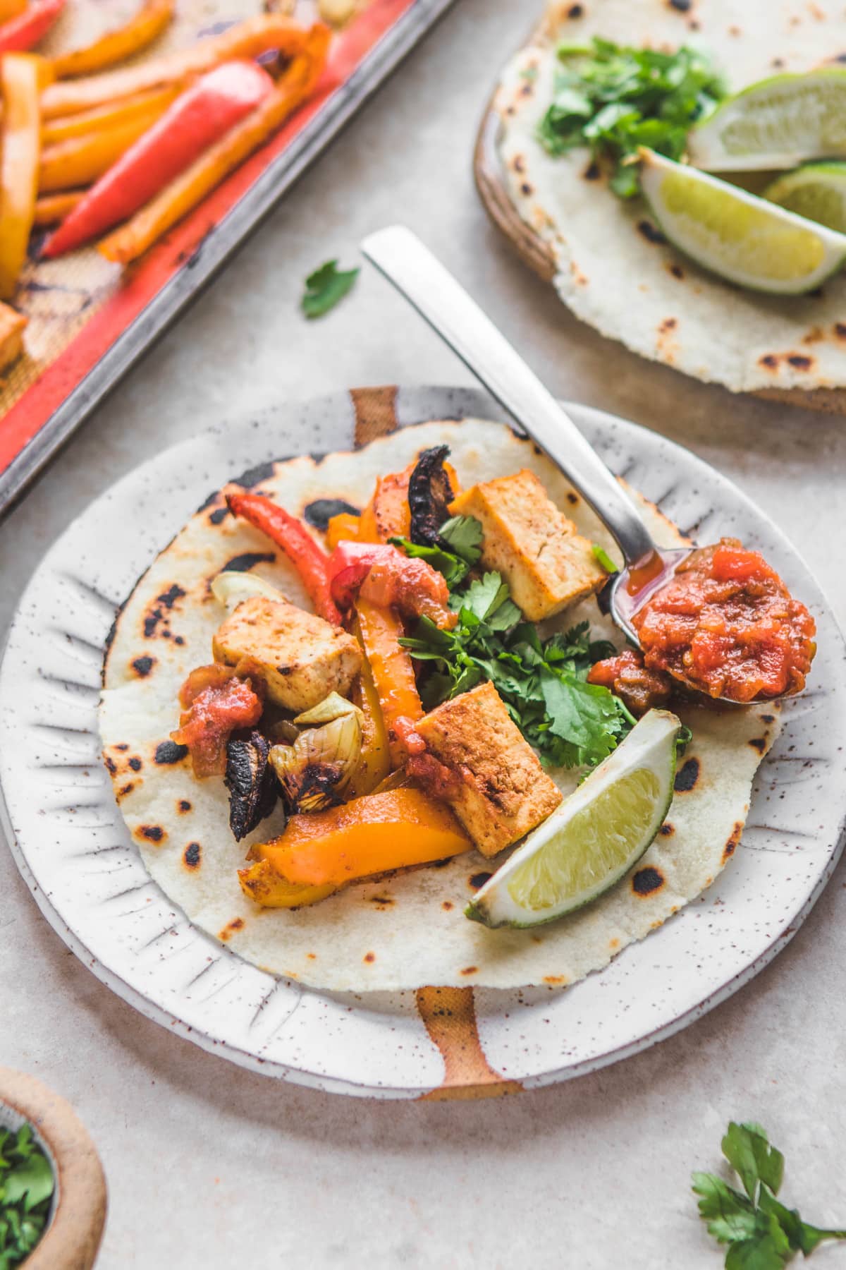 tortilla filled with tofu, roasted vegetables, and a lime wedge