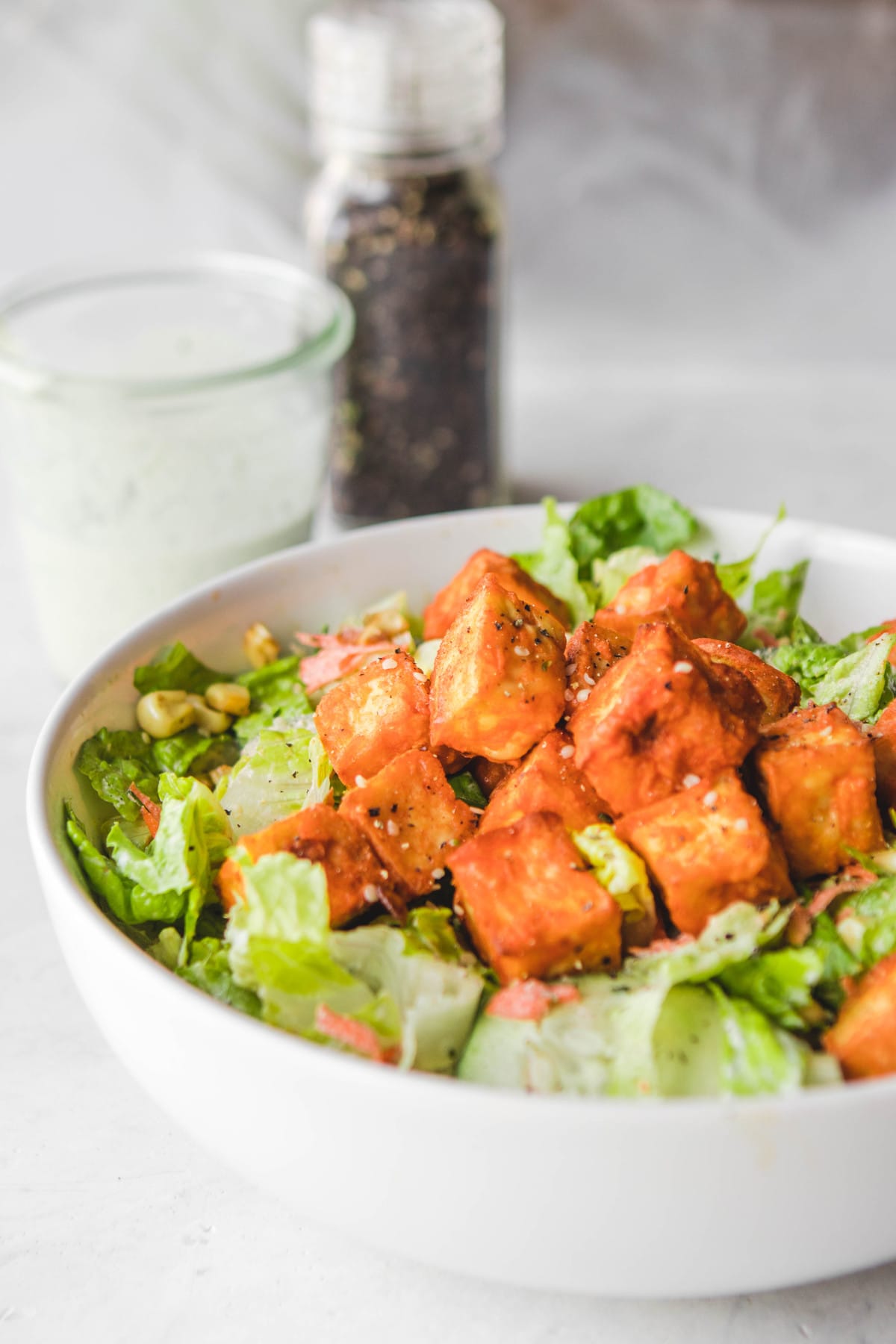 side view of buffalo tofu salad with dressing and black pepper
