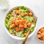 buffalo tofu salad in white bowl with gold fork