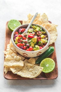 Avocado salsa on wood platter with cips