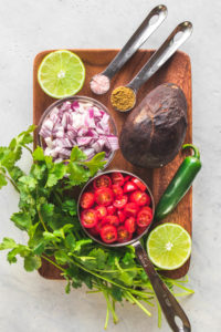 ingredients for avocado salsa on wood cutting board