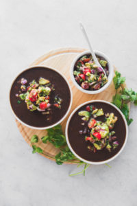 black bean soup in white bowls with salsa and cilantro