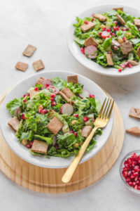 fattoush salad in white bowl with gold fork
