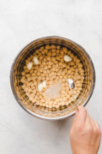 pot with soaked chickpeas, cloves of garlic, and baking soda