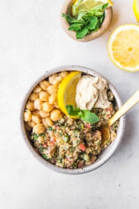 quinoa tabbouleh in white bowl with gold fork
