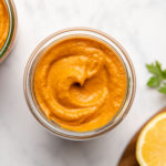 two glass jars of romesco sauce on marble background