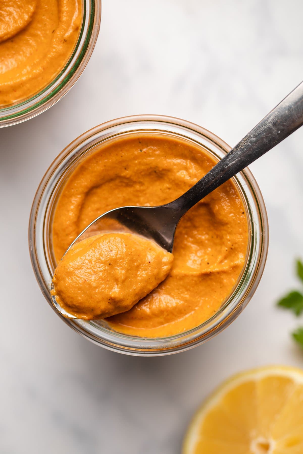 glass jar of romesco sauce with spoon scooping sauce out of jar