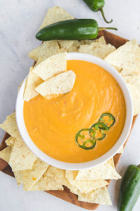 bowl of queso with chips and jalapenos