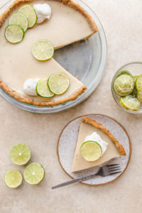 key lime pie with one slice on white plate