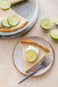 slice of key lime pie on white plate with whipped cream
