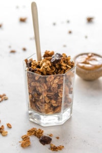 glass jar of peanut butter cup granola with peanut butter on side