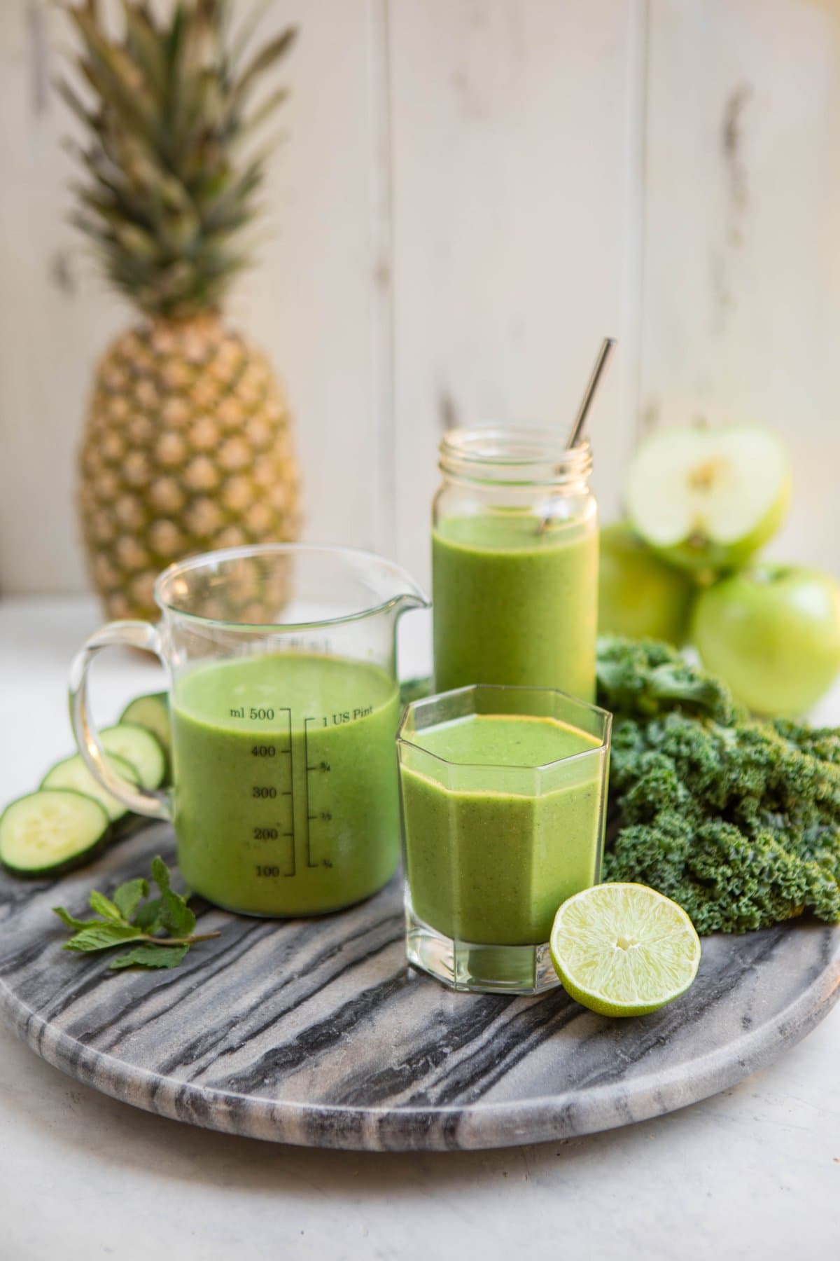 pineapple mint smoothie in glass jars on marble cutting board