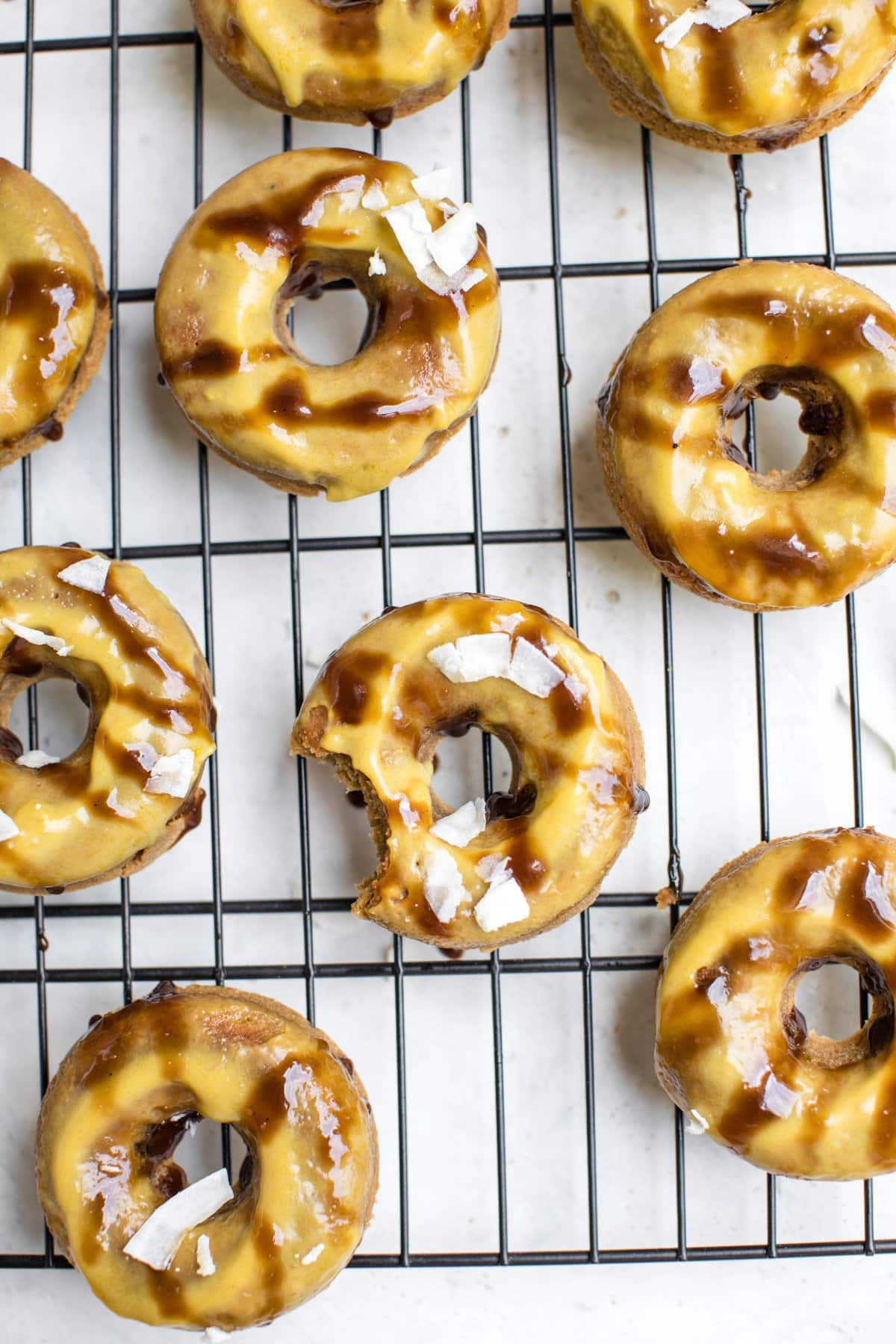 toasted coconut baked donuts on cooling rack with mango glaze