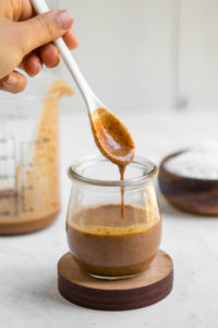white spoon drizzling coconut butter into glass jar