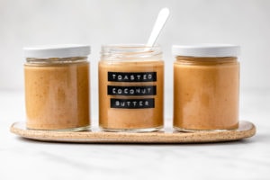 3 glass jars of toasted coconut butter with marble background