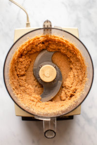 shiny and thick toasted coconut butter in food processor on marble background