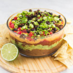 seven layer dip in glass bowl with chips