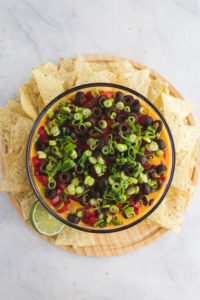 top view of seven layer dip in glass bowl with chips