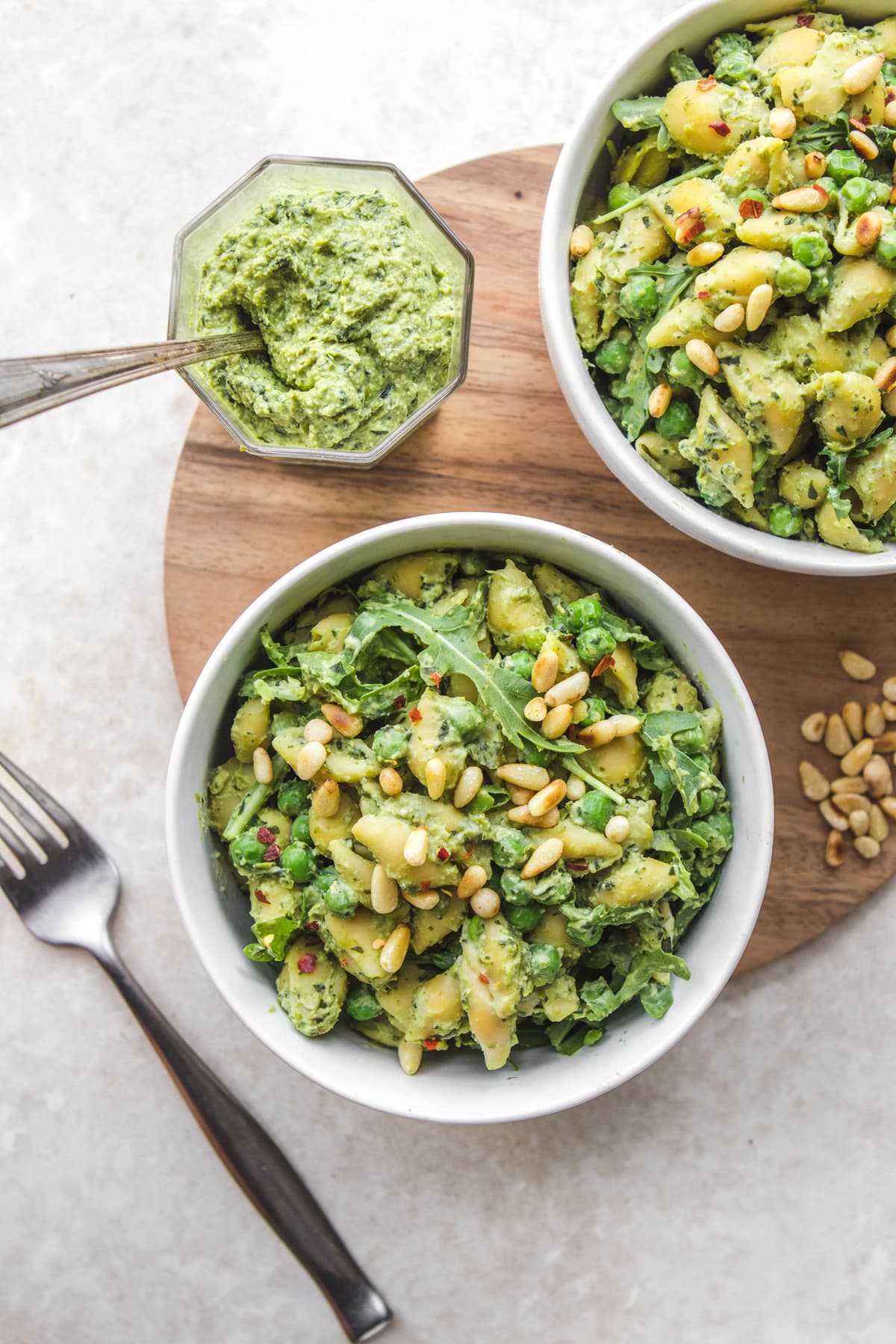 bowls of pea pesto pasta with toasted pine nuts and forks