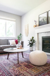 white pouf, coffee table, and couch by window