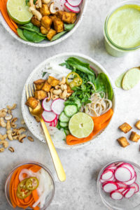 bahn mi bowl on marble background with other ingredients in small bowls around it