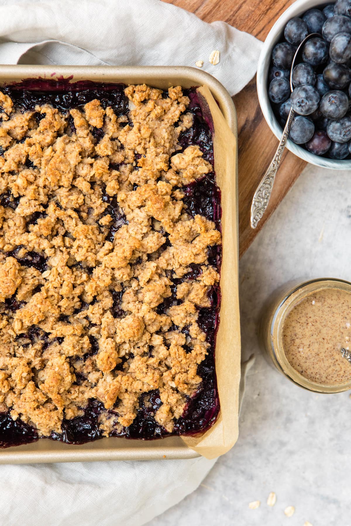 blueberry crumble bars in pan with fresh blueberries on side