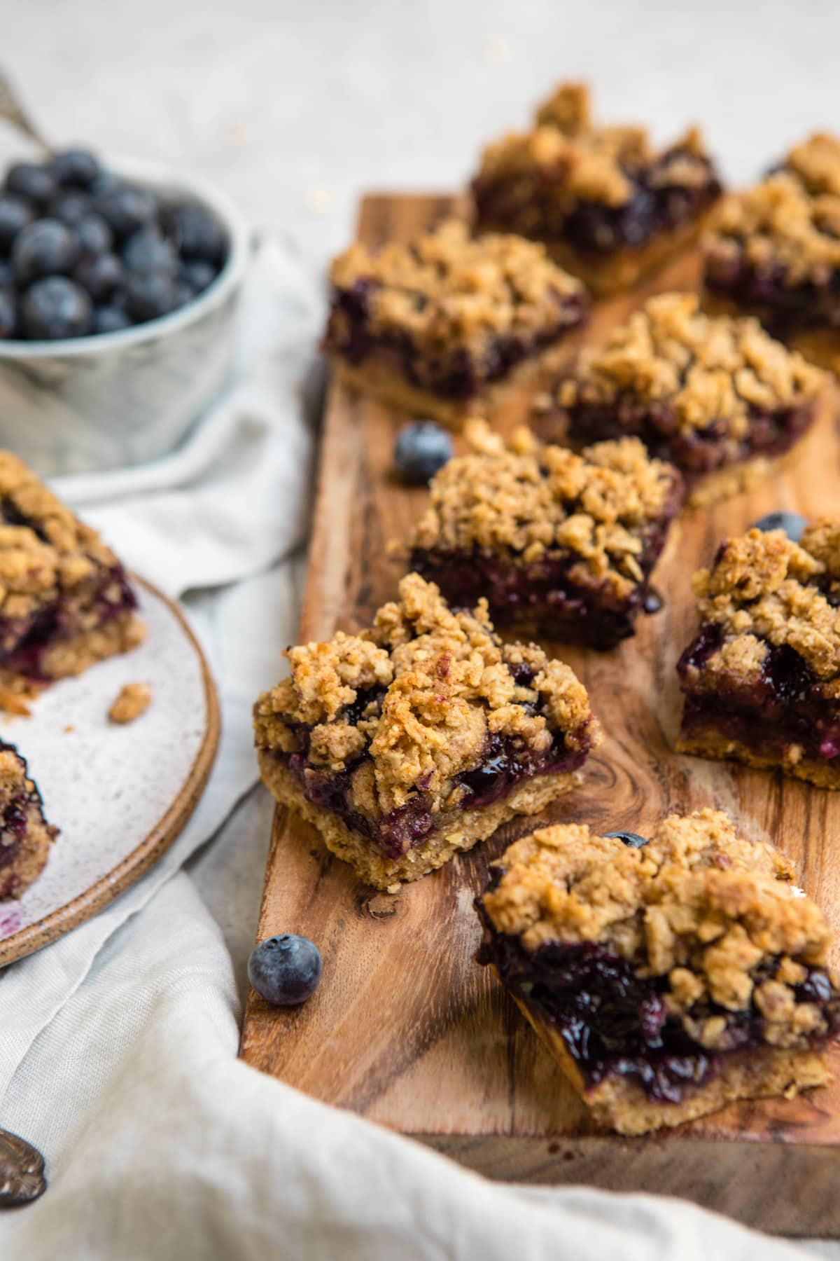 blueberry crumble bars on wooden cutting board with fresh blueberries