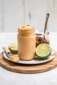 chipotle mayo in glass jar with limes on wood tray