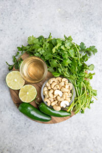 ingredients for cilantro lime dressing on round wood cutting board