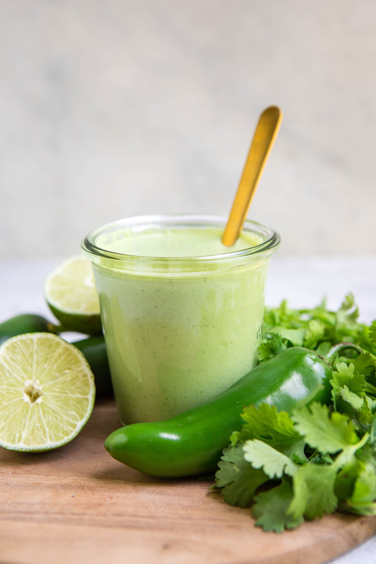 glass jar of creamy cilantro dressing with gold spoon