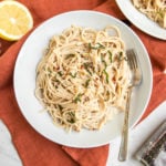 white bowl of garlic cream sauce pasta with basil and pepper