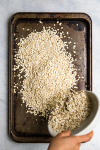 pouring bowl of oats onto baking tray
