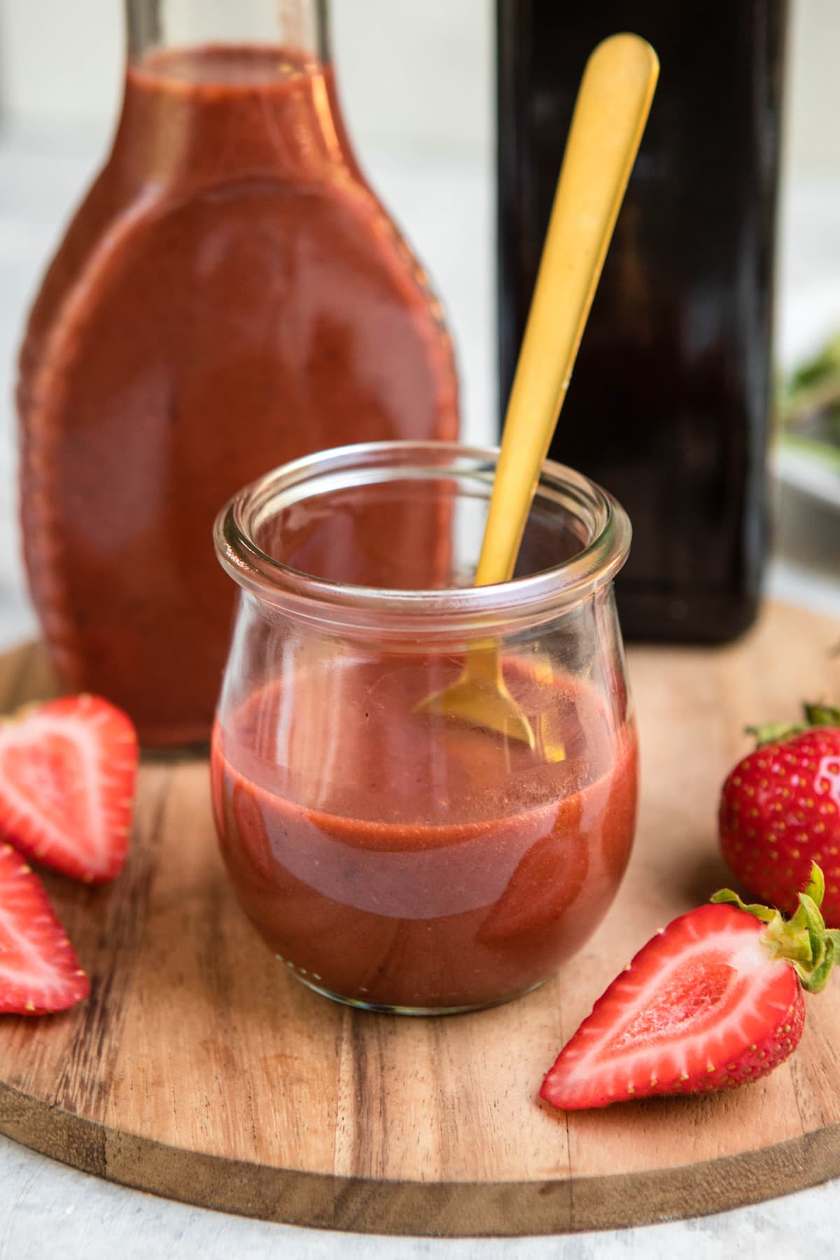 small glass jar of roasted strawberry vinaigrette with golden spoon
