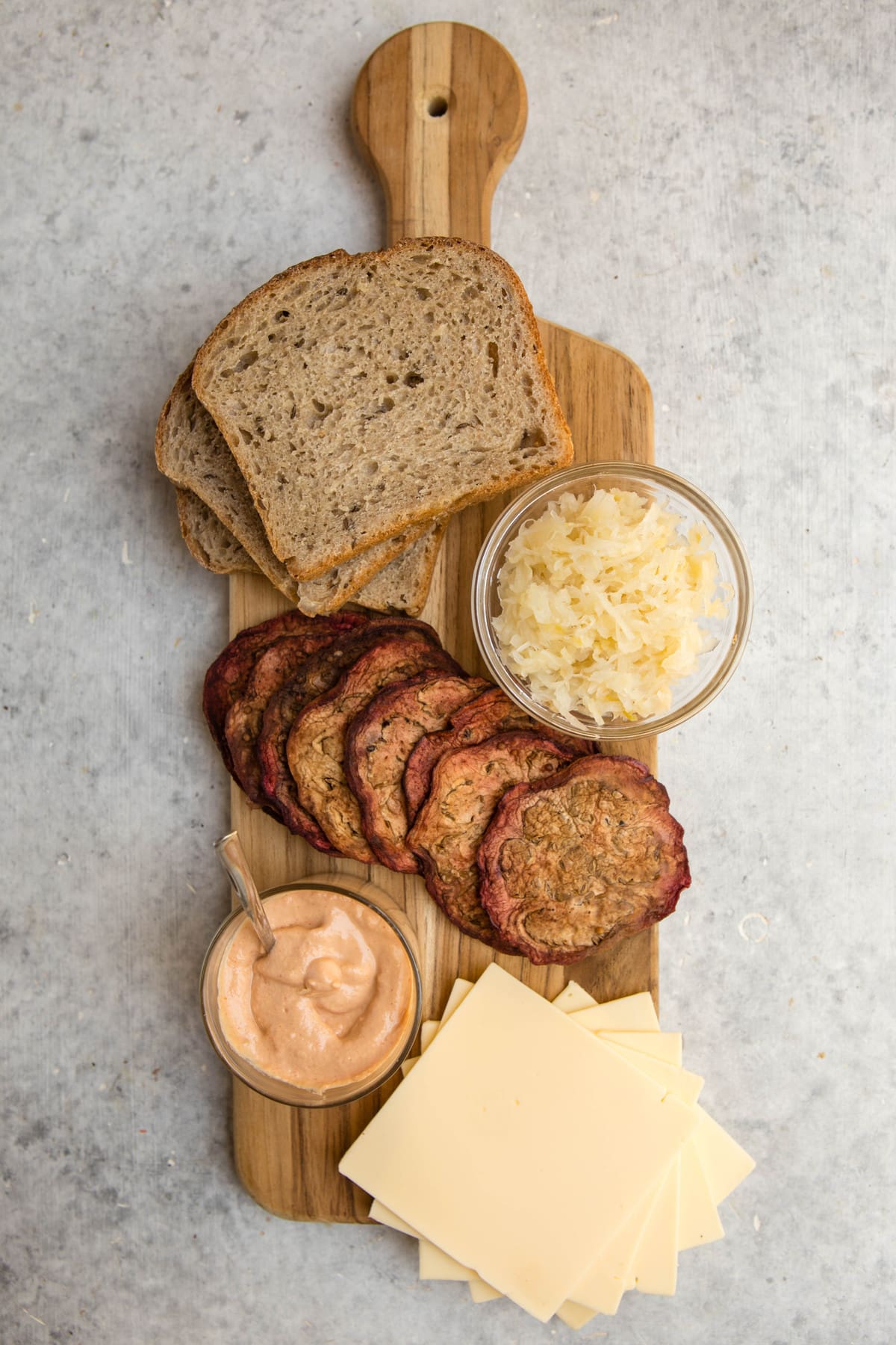 ingredients for vegan reuben sandwich on wood cutting board