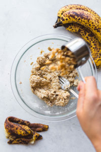 hand pouring walnuts into breakfast cookie batter